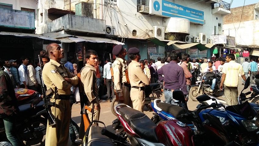 लाइन में लगे लोगों को बिस्किट और पानी देते समाजसेवी (तस्वीर- कीर्ति राजेश चौरसिया)