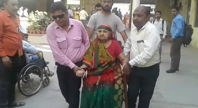 चलने में अक्षम महिला को कुर्सी पर बिठाकर ले गए बेटे